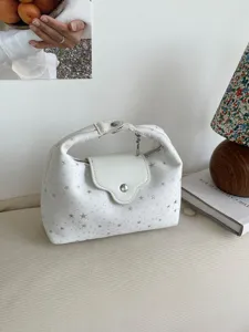 Vue détaillée d'un sac à main blanc en forme de croissant avec un motif d'étoiles argentées.