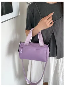 Λεπτομερής προβολή μίας μωβ νάιλον τσάντας χιαστί που φοράει ένα μοντέλο