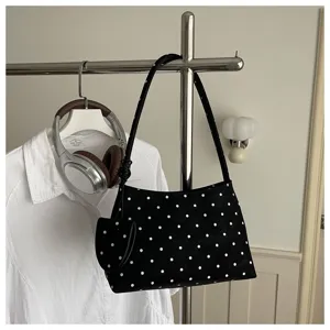 Elegante bolso de hombro con lunares blancos y negros colgado en un perchero de metal