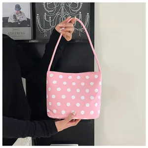 Primer plano de bolso cubo rosa con lunares resaltando los detalles del material y asa.