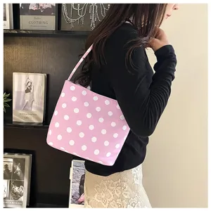 Bolso de hombro rosa con lunares llevado por una modelo en un interior acogedor