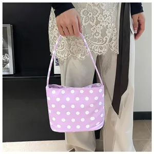 Bolso de cubo con lunares lavanda y asa superior llevado por una modelo casual ya.
