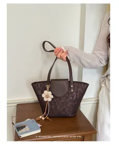 Borsa a secchiello marrone retrò con fiore in maglia su tavolo.