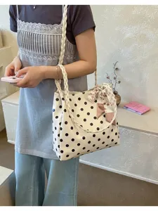Detail view of stylish polka dot tote bag with braided handles and cherry scarf