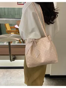 Back view of a large pink polka dot tote bag with bow detail carried on a shoulder