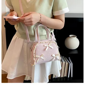 Detailansicht einer rosa Handtasche mit Spitze, Punkten und Schleifen, gehalten von einem Modell