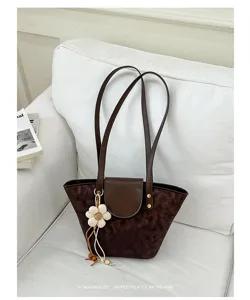 Borsa a secchiello retrò marrone con ciondolo a fiore su un divano bianco pulito
