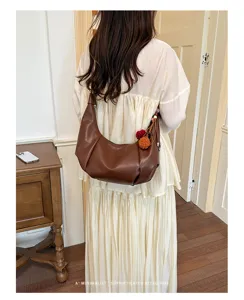 Detail of retro brown dumpling hobo bag with colorful pom-pom charm