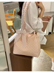 Close-up of a pink polka dot tote bag with a decorative floral bow and braided straps