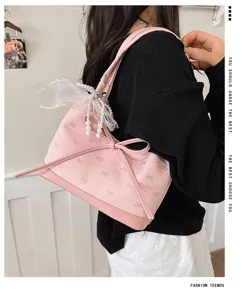 Dettaglio di una borsa rosa con fiocco e perle sulla spalla di una modella asiatica