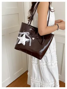 Stylish dark brown glossy tote bag with a white star plush pendant and heart charm