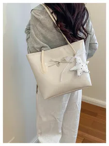 Detailed view of premium cream minimalist tote bag with decorative star charm and bow