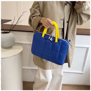 Borsa trapuntata blu per laptop con manici gialli indossata da una modella elegante