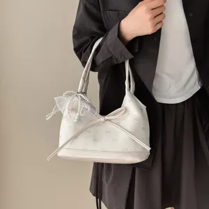 Elegante borsa sottobraccio color crema con grande fiocco e ciondolo di perle