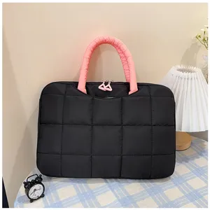 Dettaglio macro di una borsa per laptop da 14 pollici nera trapuntata con manici rosa imbottiti