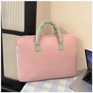 Dettaglio di una borsa per laptop rosa con manici scrunchie verde su una tovaglia