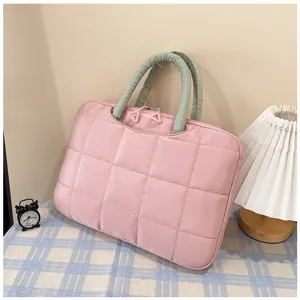 Borsa rosa trapuntata per laptop 14-16 pollici con manici verdi in un ambiente accogliente