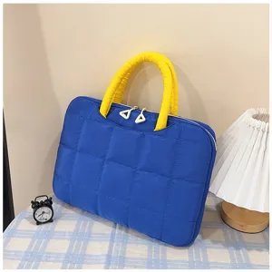 Borsa trapuntata blu e gialla per laptop su un tavolo con decorazioni casa.