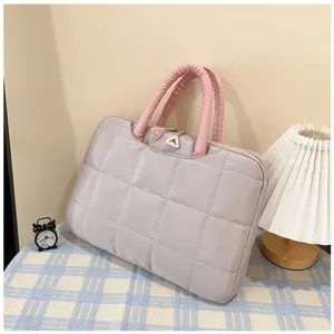 Vista dettagliata di una borsa per laptop trapuntata lavanda e rosa su una superficie a scacchi.