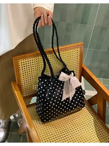 Stylish black and white polka dot tote bag with braided handles and pink floral bow.