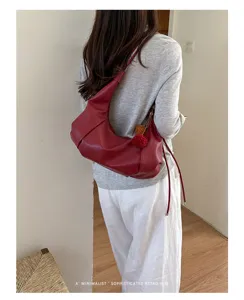 Red minimalist retro hobo bag shown being worn by a model in a cozy interior setting
