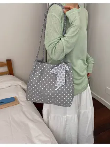 Large grey polka dot tote bag with braided straps and floral ribbon shown on model