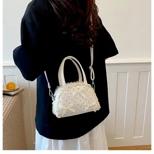 Detailaufnahme einer weißen Spitzen-Umhängetasche mit Punkten, getragen von einem Model.