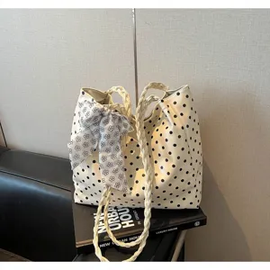 Close-up view of vintage polka dot tote bag with braided handles and floral bow