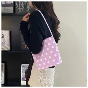 Vista detallada de un bolso bombonera lila con lunares llevado por una modelo real