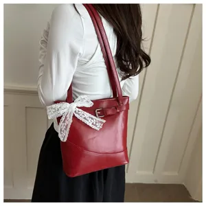 Dettaglio di una borsa a tracolla rossa con fiocco in pizzo bianco e fibbia