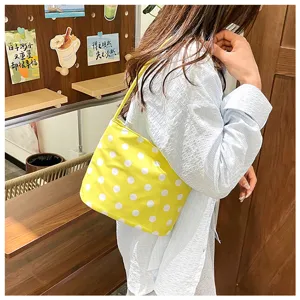 Detalle de bolso de hombro amarillo con lunares llevado por una modelo en entorno casual