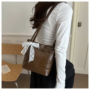Dettaglio della borsa tote marrone da pendolare con fiocco in pizzo bianco