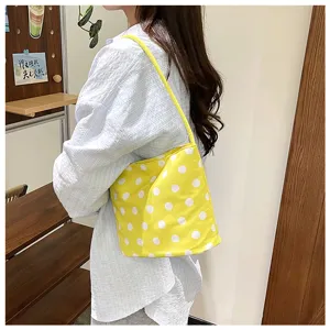 Vista detallada del bolso cubo amarillo con lunares llevado por modelo en interior