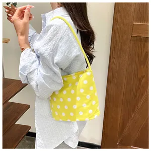 Bolso cubo amarillo con lunares llevado al hombro por una modelo