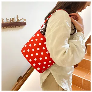 Primer plano detallado de un bolso tipo cubo rojo con lunares blancos para mujer