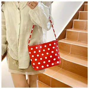 Primer plano de un elegante bolso de hombro rojo con lunares llevado por modelo