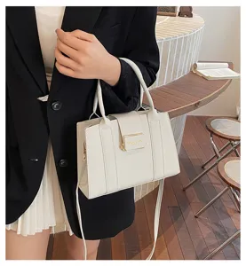 Macro view of white leather tote bag featuring elegant gold-tone hardware and handle detail