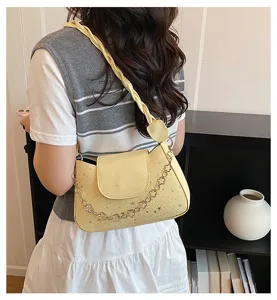 Détail d'un sac à bandoulière jaune avec une sangle tressée et un motif d'étoile