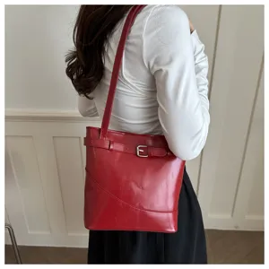 Elegante borsa a secchiello in ecopelle rossa con fibbia decorativa portata sulla spalla