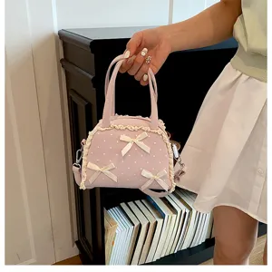 Rosa gepunktete Handtasche mit Spitzenbesatz und Schleifen, von einer Person getragen