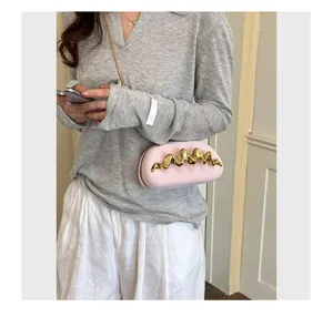 Dettaglio mini borsa a tracolla rosa con decoro dorato ondulato per serate eleganti.