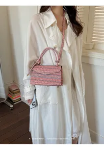 Dettaglio di una mini borsa in tweed rosa abbinata a una camicia di lino bianca oversize