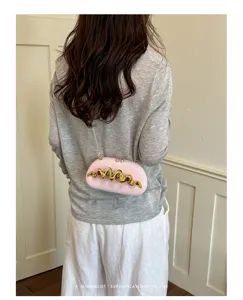Elegante borsa da sera rosa con dettaglio dorato ondulato, indossata da una modella fiera.