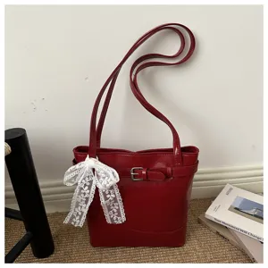 Elegante borsa a secchiello rosso scuro con fibbia e fiocco in pizzo bianco.