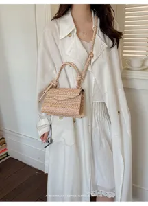 Dettaglio di una borsa intrecciata chic indossata da una modella in cappotto bianco