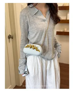 Borsa da sera bianca minimalista con dettaglio dorato indossata da una modella
