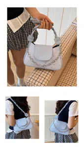 Détail d'un sac à bandoulière bleu clair à motif étoilé avec sangle tressée et chaîne dorée.
