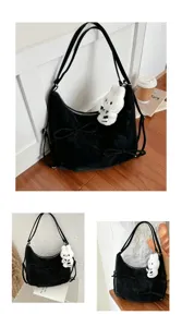 Detail of large black velvet tote bag featuring ribbon bows and white plush rabbit charm