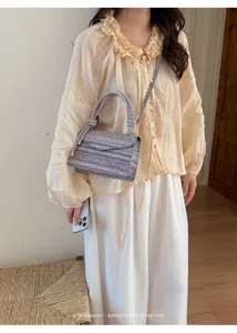 Dettaglio ravvicinato della borsa a tracolla in tweed con estetica retrò minimalista.