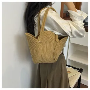Modèle portant un sac bandoulière tissé main kaki avec un design unique en pétales.